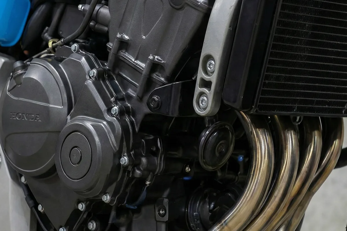 Detalhe do motor Honda de 4 cilindros com coletores de escape cromados e radiador, em uma CG customizada.
