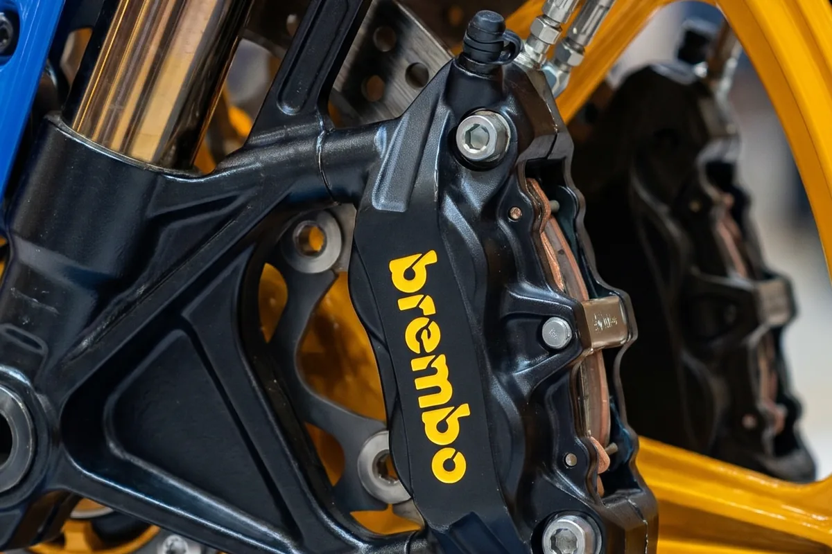 Close-up da pinça de freio dianteira Brembo preta com logotipo amarelo e disco da Yamaha Tenere 600 Concept.