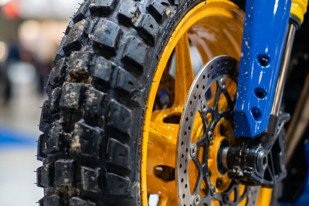 Close-up da roda dianteira dourada com pneu off-road e disco de freio da Yamaha Tenere 600 Concept.